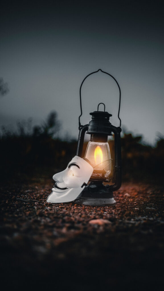 Mysterious Guy Fawkes Mask beside an Antique Lantern Mobile Wallpaper