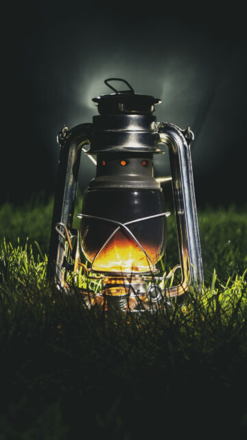 Glowing Vintage Kerosene Lantern on Grass Mobile Wallpaper