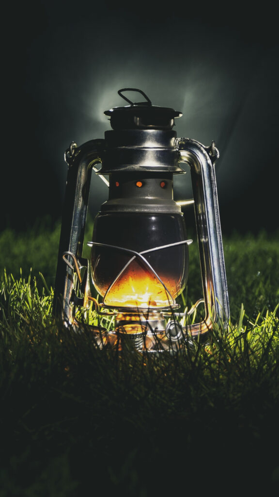 Glowing Vintage Kerosene Lantern on Grass Mobile Wallpaper