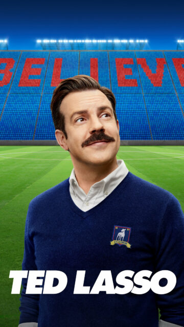Ted Lasso Standing Before The Believe Stadium Sign Mobile Wallpaper