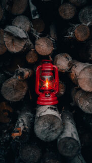 Red Oil Lantern on Stacked Firewood Mobile Wallpaper