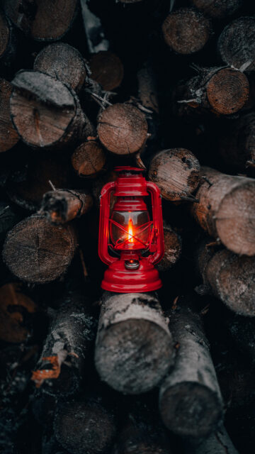 Red Oil Lantern on Stacked Firewood Mobile Wallpaper