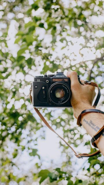 Vintage Zenit 11 Film Camera Held Against Bokeh Trees Wallpaper