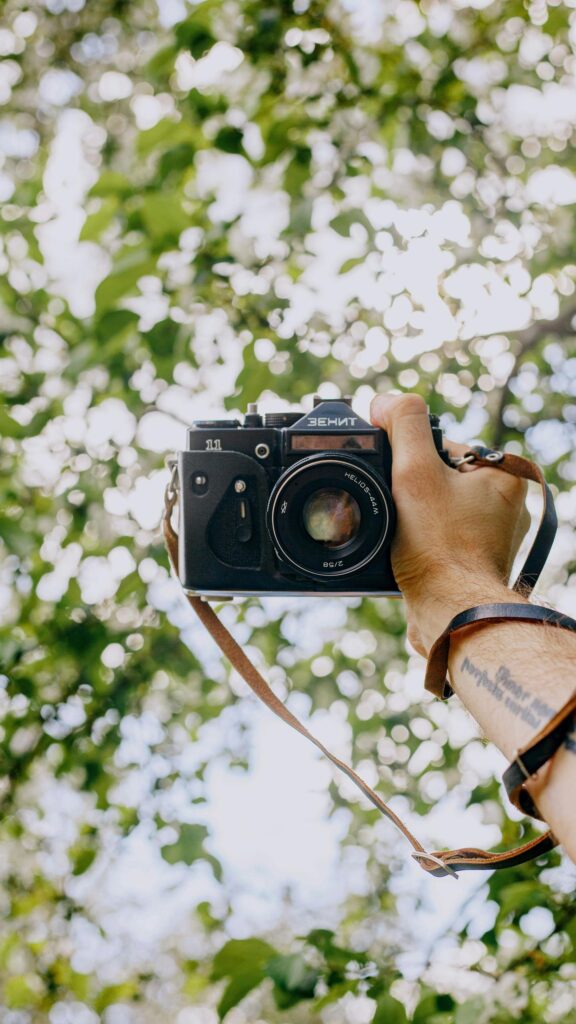 Vintage Zenit 11 Film Camera Held Against Bokeh Trees Wallpaper