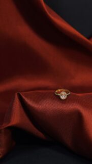 Elegant Gold Engagement Ring on Rich Red Silk Fabric Wallpaper