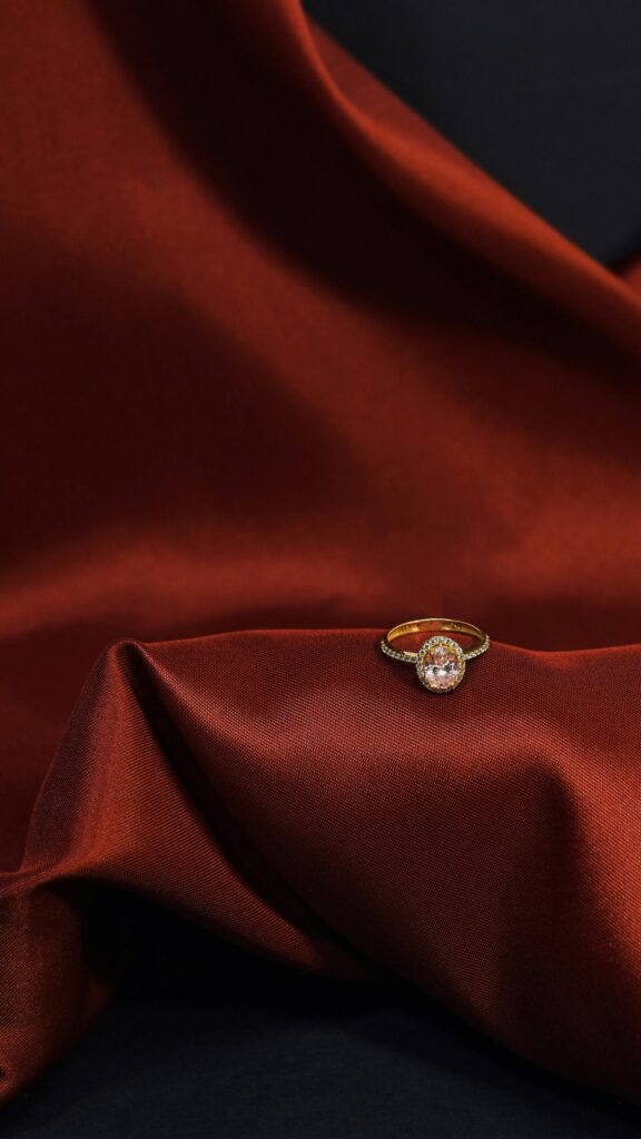 Elegant Gold Engagement Ring on Rich Red Silk Fabric Wallpaper