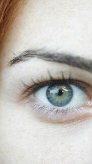 Striking Blue and Green Eye Close-up with Red Hair Mobile Wallpaper