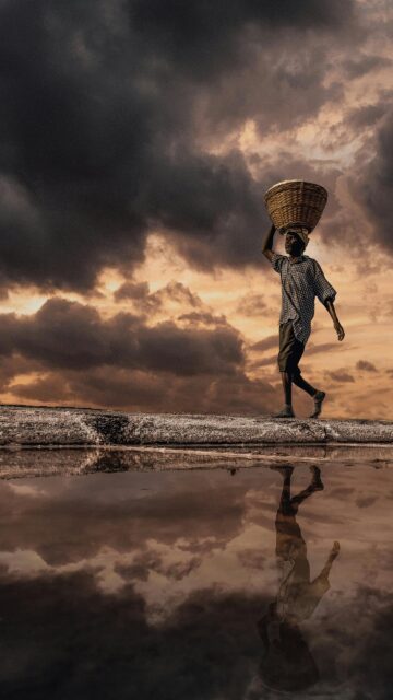 Stunning Salt Farmer Silhouetted Against Dramatic Stormy Sky Phone Wallpaper