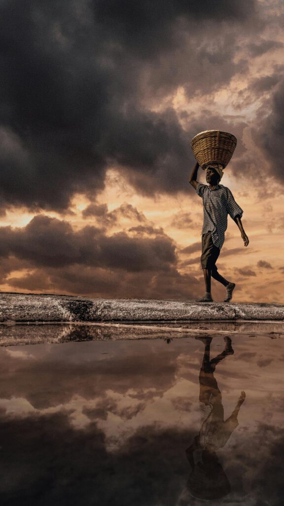 Stunning Salt Farmer Silhouetted Against Dramatic Stormy Sky Phone Wallpaper