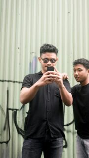 Two Young Men Checking Phone Against Graffiti Metal Wall Wallpaper