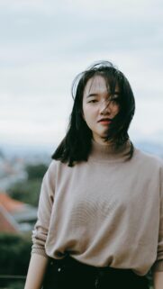 Asian Girl with Windblown Hair in Tan Sweater Phone Wallpaper