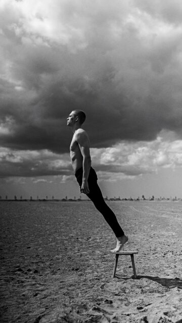 Surreal Man Levitating on a Stool Minimalist Black and White Wallpaper