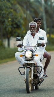 Two Men Riding Vintage Motorcycle Rural Road Mobile Wallpaper