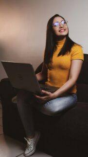 Young Woman Using Laptop in Yellow Shirt Mobile Wallpaper