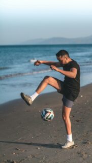 Athletic Soccer Player Training on Sandy Beach Mobile Wallpaper