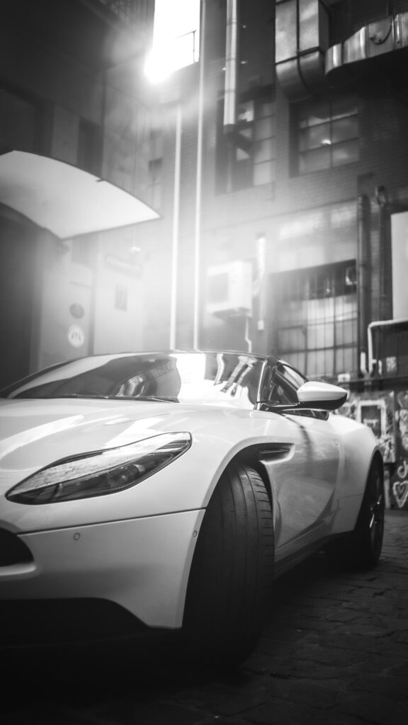 Luxury Aston Martin Sports Car in Urban Alleyway Monochrome Wallpaper