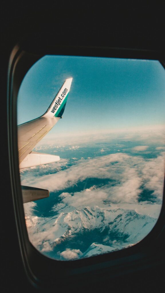 Aerial View of Snowy Mountains and WestJet Wing Plane Wallpaper