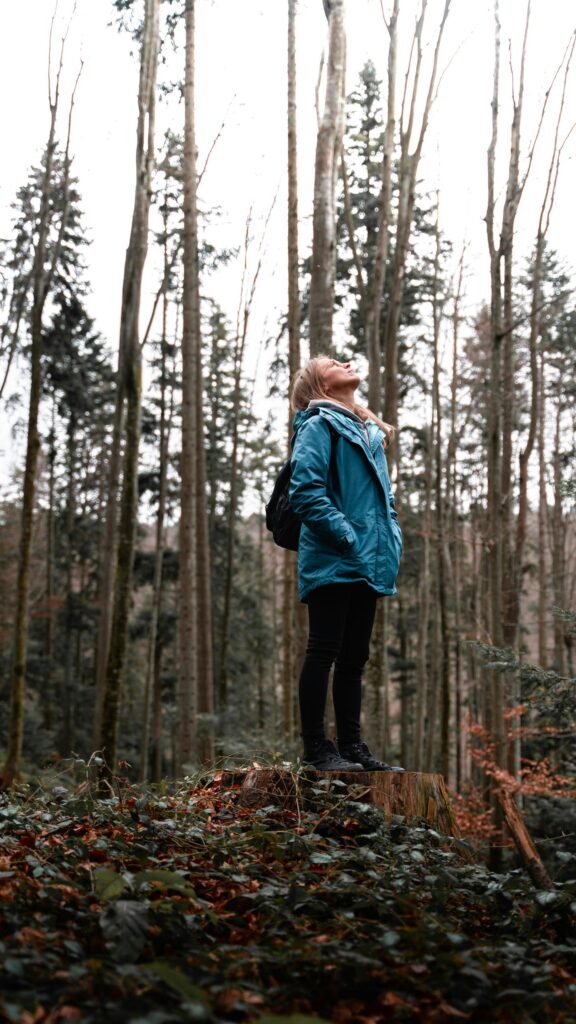 Woman Standing on Tree Stump in Forest Adventure Mobile Wallpaper