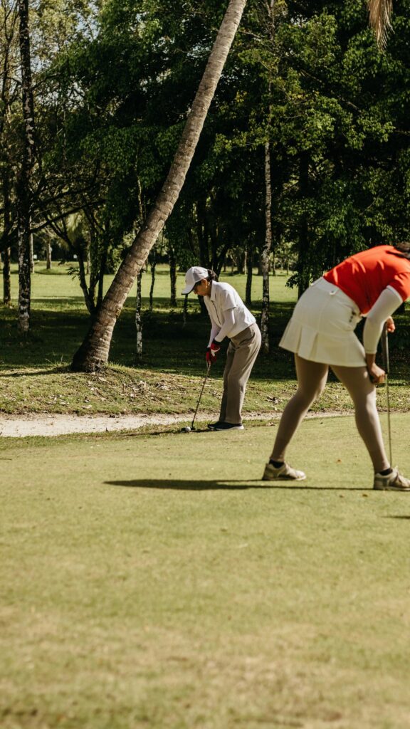Two Women Playing Golf on Sunny Green Course Phone Wallpaper