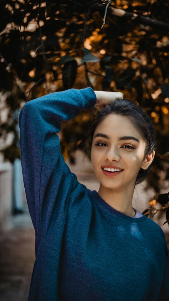 Beautiful Young Woman Posing Under Autumn Trees Mobile Wallpaper