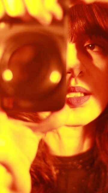 Fiery Aesthetic Girl Holding Camera Portrait Mobile Wallpaper