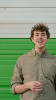 Young Man Smiling in Sage Green Shirt Portrait Mobile Wallpaper