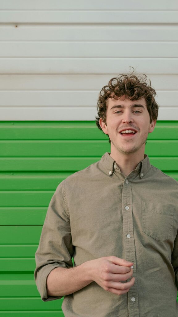 Young Man Smiling in Sage Green Shirt Portrait Mobile Wallpaper