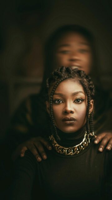 Stunning Portrait of a Woman with Braids and Gold Necklace Wallpaper