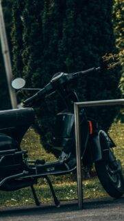 Vintage Black Vespa Scooter Parked in Lush Greenery Wallpaper
