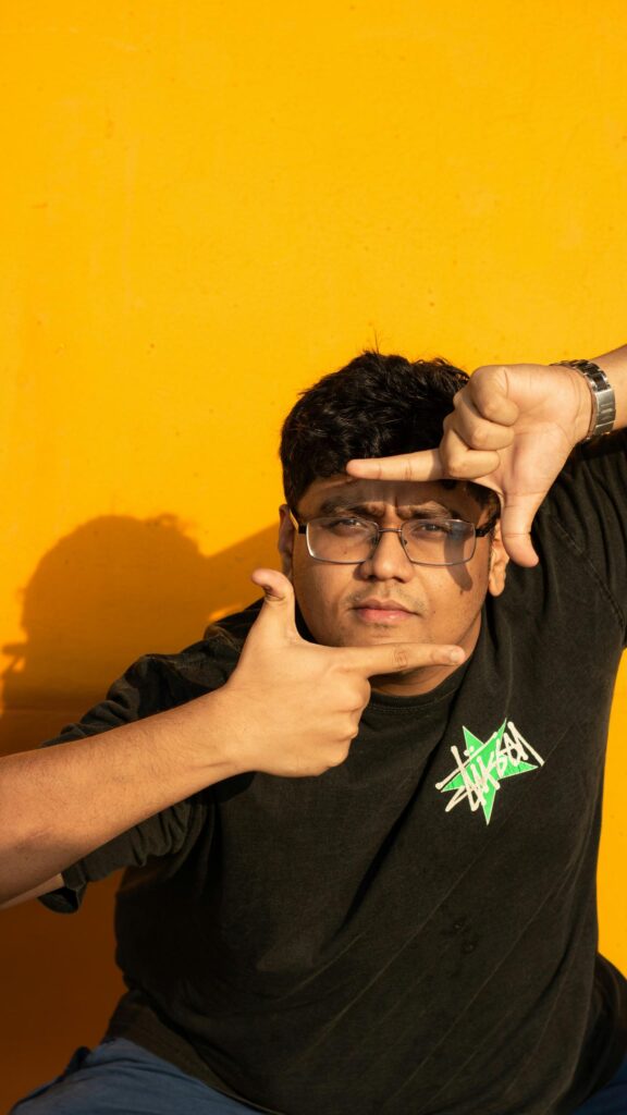 Creative Portrait of a Young Man Framing His Face Yellow Background Wallpaper