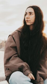 Stunning Portrait of a Woman with Long Dark Hair in a Brown Jacket Wallpaper