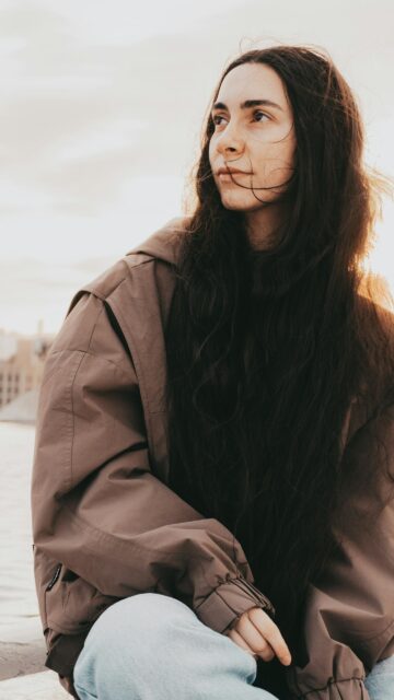 Stunning Portrait of a Woman with Long Dark Hair in a Brown Jacket Wallpaper