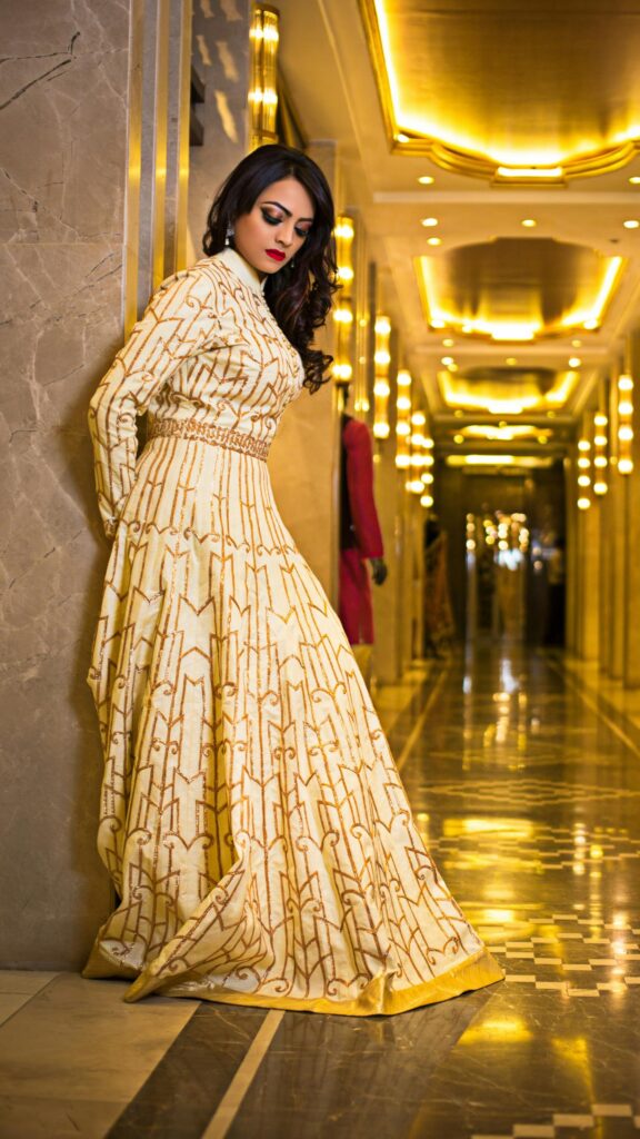 Elegant Woman in Gold Embroidered Gown Standing in Luxury Hallway Wallpaper