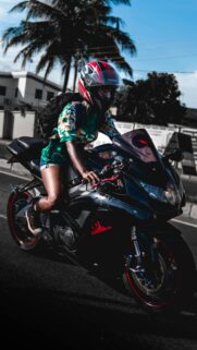 Biker Girl Riding Black Sports Bike at Sunset Mobile Wallpaper