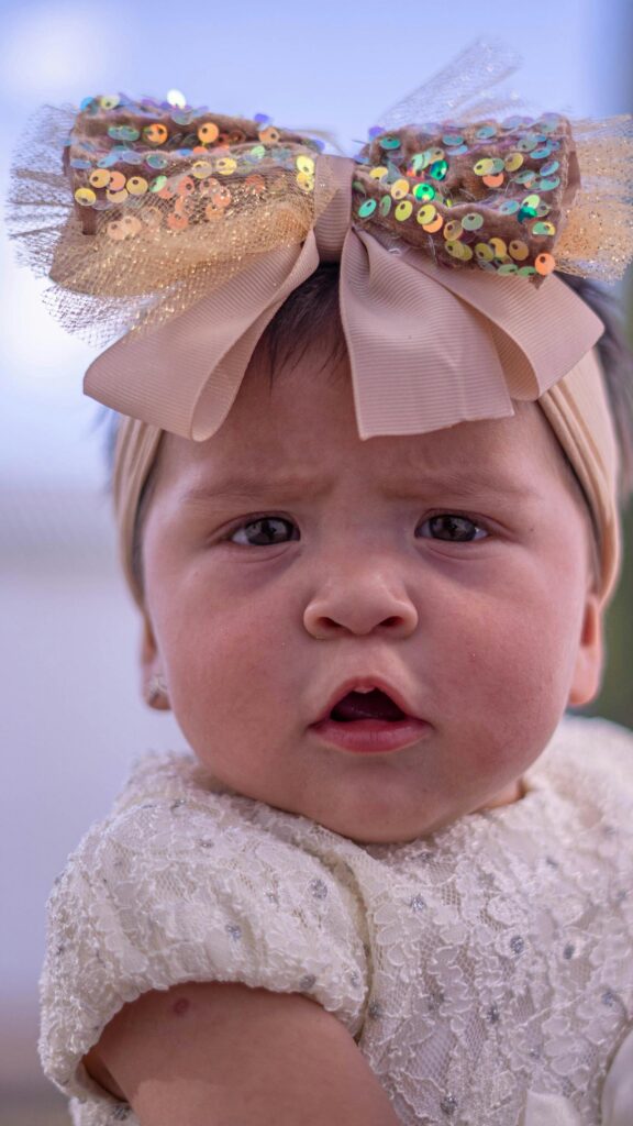 Adorable Baby Girl with Sparkly Gold Bow Mobile Wallpaper