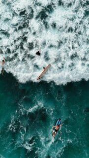 Aerial View of Surfers Riding Ocean Waves Mobile Wallpaper