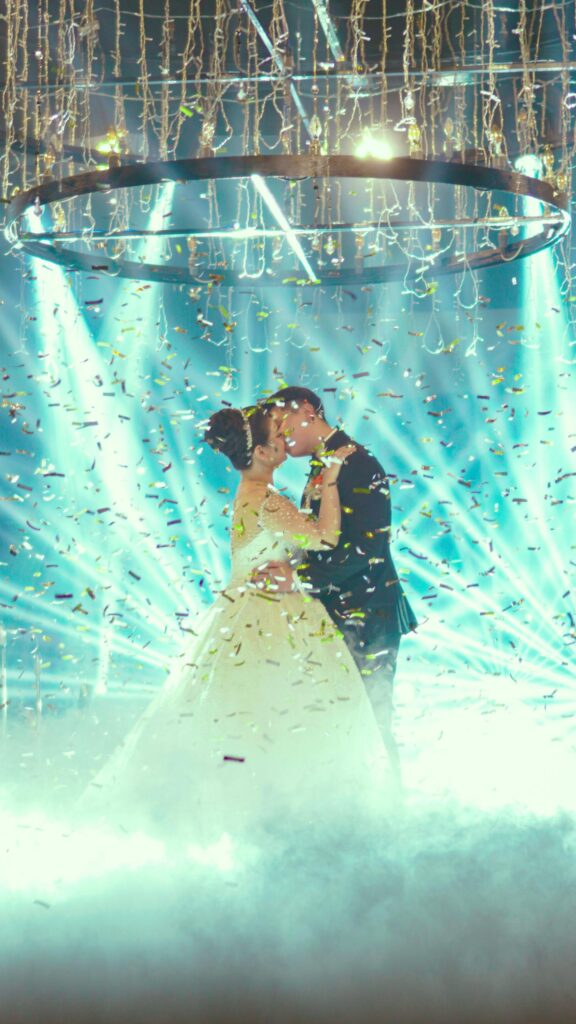Stunning Romantic Wedding Couple Kissing Under Confetti Lights Wallpaper