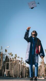 Celebrating Graduation Day Stylish Young Man Tossing Cap Wallpaper