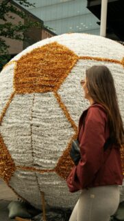 Woman Beside Large Gold and White Decorative Soccer Ball Wallpaper