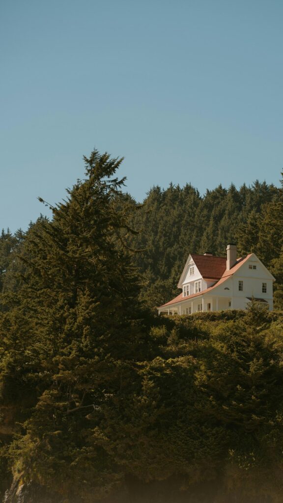 Serene White Colonial House Nestled in Coastal Forest Wallpaper