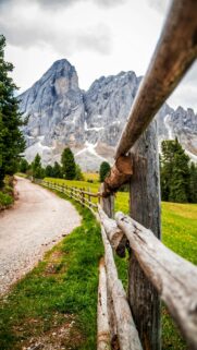 Majestic Dolomites Mountain Road with Rustic Wood Fence Wallpaper