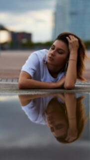 Stunning Young Woman Posing by a Water Reflection Phone Wallpaper