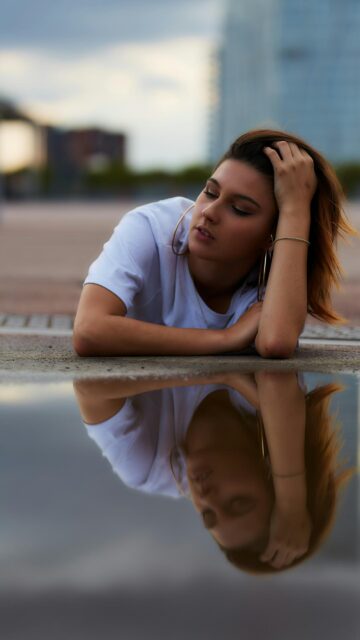 Stunning Young Woman Posing by a Water Reflection Phone Wallpaper