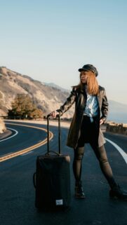 Stylish Traveler on Coastal Road Portrait Mobile Wallpaper