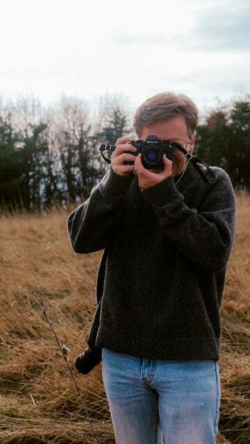Photographer with Vintage Nikon Camera in Golden Field Wallpaper
