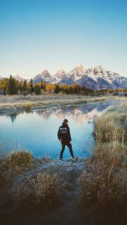 Adventurous Person Standing by Reflection Mountain Lake Wallpaper