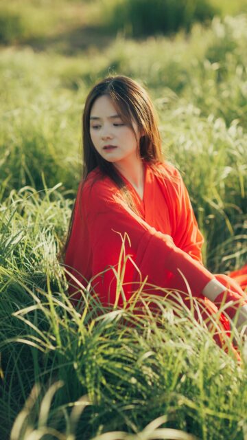 Beautiful Woman in Traditional Red Dress Sitting in Grass Wallpaper