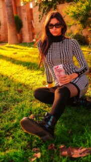 Stylish Woman in Houndstooth Dress Sitting on Grass Mobile Wallpaper