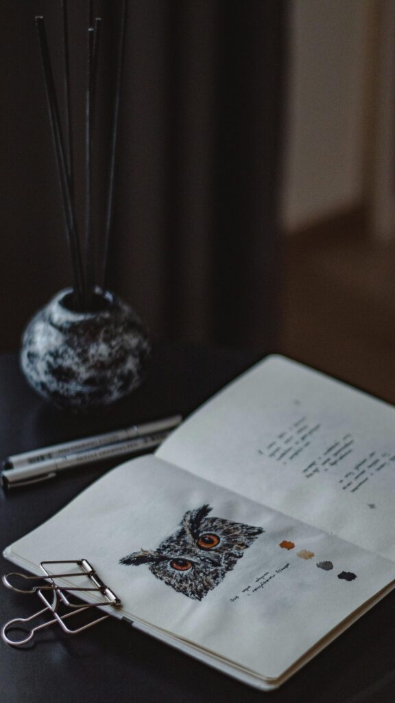 Artistic Owl Sketch in Open Notebook on Dark Desk Wallpaper