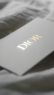 Elegant Dior Logo Gold Embossed on Grey Background Phone Wallpaper